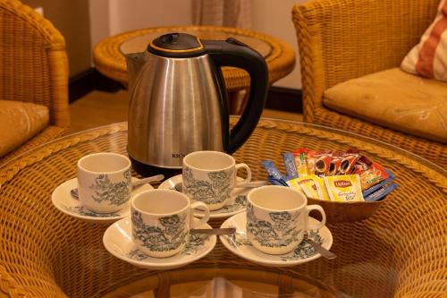 a tea kettle and saucers on a coffee table at Hotel Puri Melaka in Malacca
