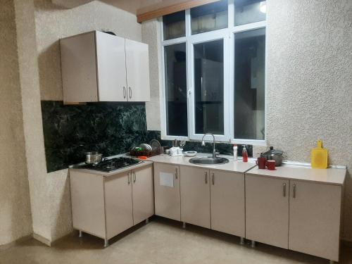 a kitchen with white cabinets and a sink and a window at GIORGI kvariati in Kvariati