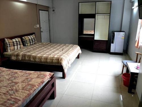 a hotel room with two beds and a refrigerator at โรงแรม นิววันชัย โฮเต็ล in Ban Sao Thong