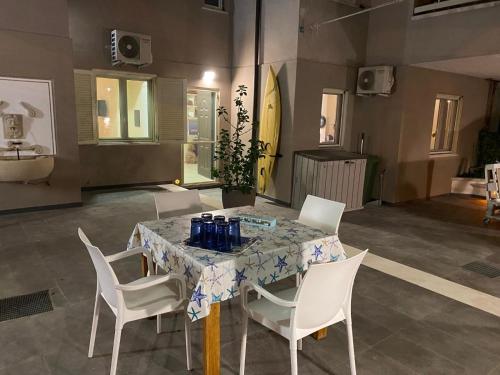 a dining table with white chairs and a table with blue bottles on it at ISCA BLUE BEACH Casa in Villa vicino al mare, sino a max 8 persone in Isca sullo Ionio