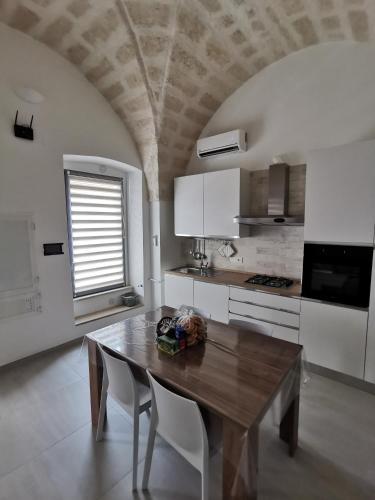a kitchen with a wooden table and white cabinets at A Casa di Tina in Crispiano