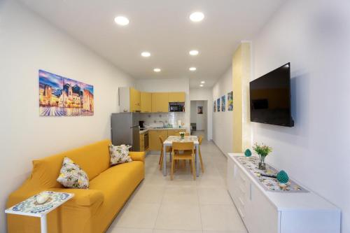 a living room with a yellow couch and a kitchen at Kris Luxury Apartments in Giardini Naxos