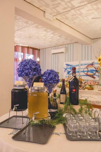 a table with bottles of wine and glasses and flowers at Hotel Stella Del Mare in Cervia