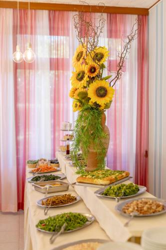 a long table with plates of food and a vase of flowers at Hotel Stella Del Mare in Cervia