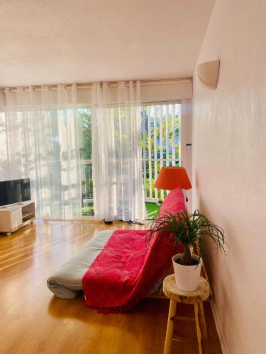 - une chambre avec un lit rouge dans une pièce avec une fenêtre dans l'établissement T2 à 50 mètres de la mer, belle vue sur végétation, à Saint-Raphaël