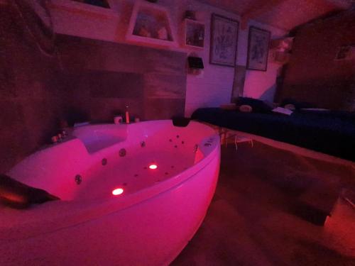 uma banheira rosa num quarto com um sofá em La Battigia B&B em Trabia