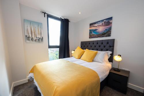 a bedroom with a bed with yellow sheets and a window at Contemporary 3 Bedrooms Apartment Manchester City in Manchester