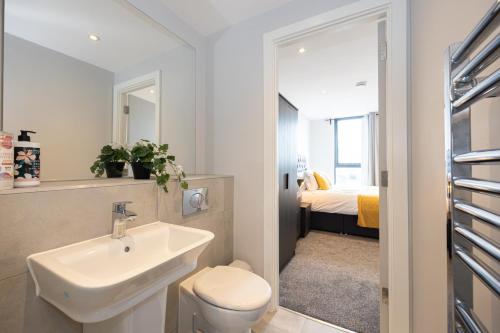 a bathroom with a sink and a toilet and a bedroom at Contemporary 3 Bedrooms Apartment Manchester City in Manchester