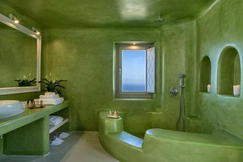 un bagno verde con vasca e lavandino di Skyfall Suites - Adults Only a Pyrgos