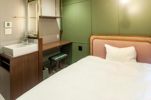a small bathroom with a bed and a sink at Mito Sannomaru Hotel in Mito