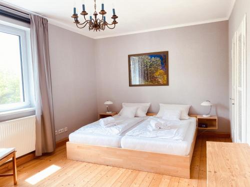 Schlafzimmer mit einem weißen Bett und einem Kronleuchter in der Unterkunft Ruhig, modern & Nähe Altstadt! in Meiningen