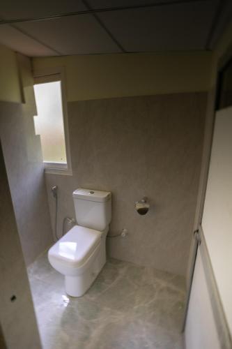 a white toilet in a bathroom with a window at The Thick Forest in Sigiriya