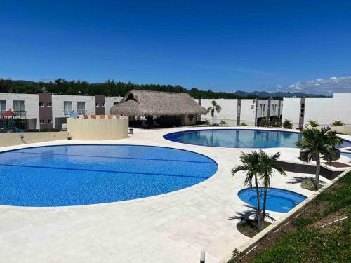 2 piscinas grandes con palmeras y un edificio en Bellísima casa para descansar, en Ricaurte