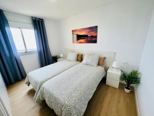 a bedroom with two beds and a plant in it at Torres del Sol Playa de Las Vistas FREE WIFI in Playa de las Americas