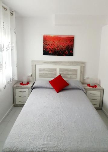 a bedroom with a white bed with a red pillow at La Pedrera Font Nova in Peniscola