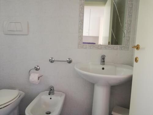 a bathroom with a sink and a toilet and a mirror at la raganella - appartamento in Procchio