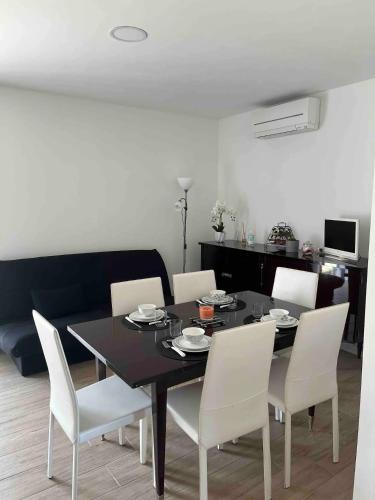 a dining room with a black table and white chairs at Cocon aux portes des Cévennes avec piscine in Moulès-et-Baucels