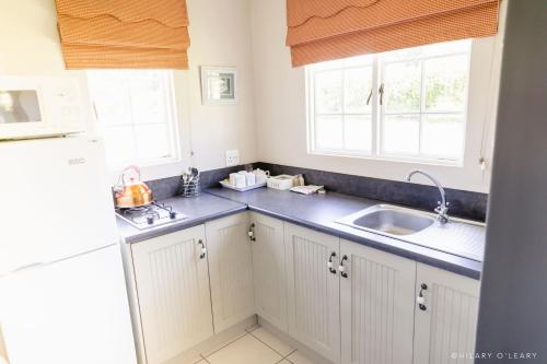 a kitchen with white cabinets and a sink and a window at Old Rearsby in Mooirivier