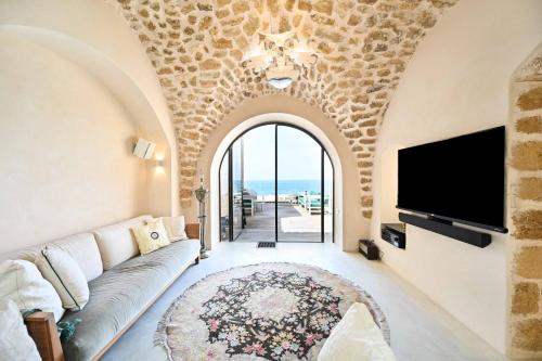 a living room with a couch and a tv at Outstanding Old Jaffa Villa facing the Sea by HolyGuest in Tel Aviv