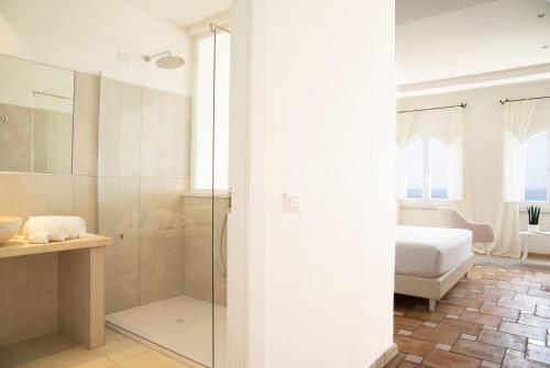 a bathroom with a glass shower and a bed at Relais La Ghinghetta in Portoscuso