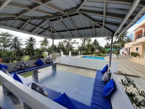 um pátio com almofadas azuis e um guarda-sol junto a uma piscina em Maison De Gloria em Locsin