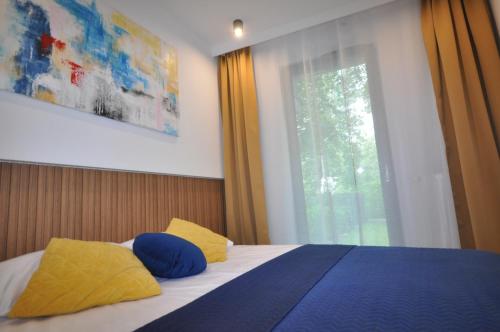 a bedroom with a bed with blue and yellow pillows at Krakowskie Malediwy by JoApart - Tauron Arena, Expo in Krakow