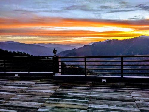 a sunset over the mountains with a fence at THE GETAWAY in Shimla