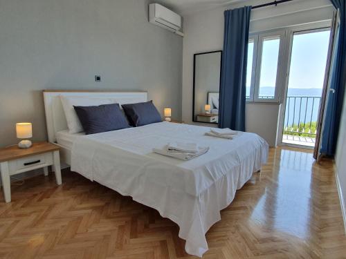 a bedroom with a large white bed and a large window at Apartman Oneum in Omiš