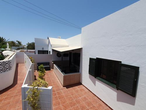 ein weißes Haus mit einer Terrasse mit Topfpflanzen in der Unterkunft Casa El Eco del Volcán 1 in Teguise