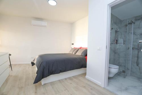 a white bedroom with a bed and a shower at Beachfront Elegance - Luxe Abode! in Netanya