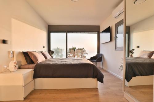 Un dormitorio con una cama y una ventana grande. en Beachfront Elegance - Luxe Abode!, en Netanya