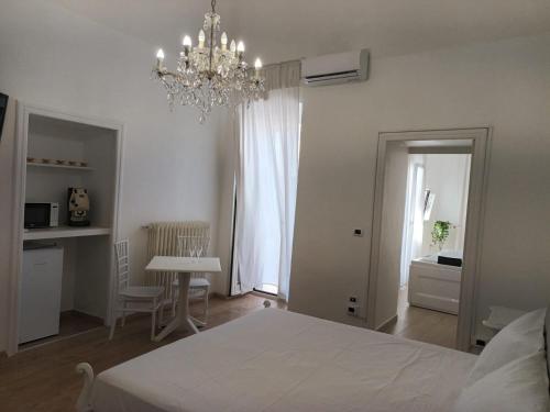 um quarto com uma cama branca e um lustre em Geometric Hermes Bianca em Palo del Colle