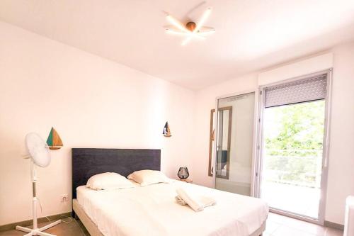 - une chambre blanche avec un lit et un ventilateur de plafond dans l'établissement O'Cap YourHostHelper, à Antibes