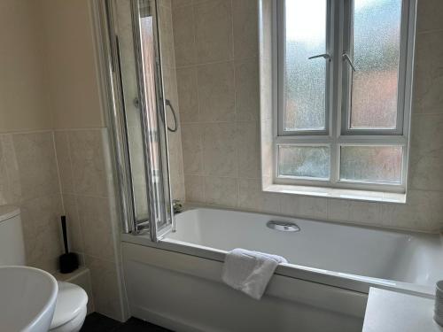 łazienka z wanną, toaletą i oknem w obiekcie Cosy 2 Bedrooms 2 Bathrooms w mieście Basingstoke