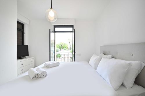 a white bedroom with a white bed and a tv at NOGA vibes 2BR in JAFFA by Holyguest in Tel Aviv