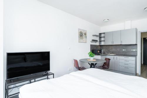a white bedroom with a white bed and a table at Apartmán v Poděbradech in Poděbrady