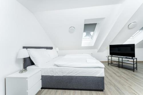 a white bedroom with a bed and a flat screen tv at Apartmán v Poděbradech in Poděbrady