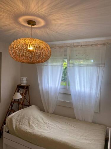 - une chambre dotée d'un lit avec des rideaux blancs et un lustre dans l'établissement Logement au calme près d'Aurillac, à Sansac-de-Marmiesse