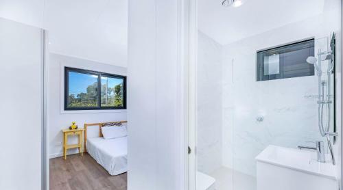 een witte badkamer met een bed en een douche bij New Gymea House in Gymea