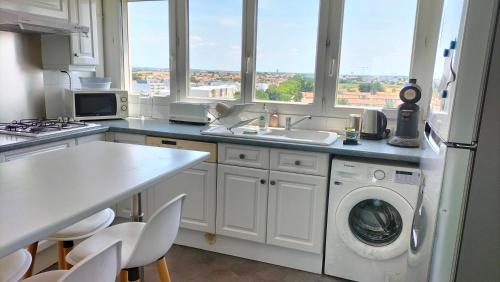une cuisine avec un évier et une machine à laver dans l'établissement Grand appartement lumineux vue mer, à La Rochelle
