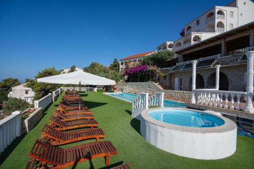a row of chairs and a swimming pool with an umbrella at Garden Resort - Apartments Maslina in Potocnica