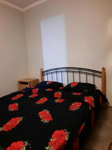 a bedroom with a bed with a black blanket with red flowers at Однокомнатная квартира от городской суеты in Gyumri