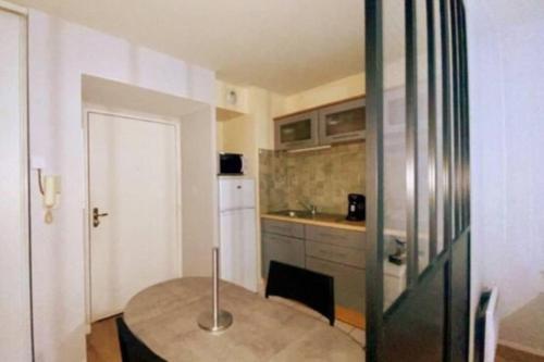 a small kitchen with a table and a refrigerator at Les Grenats in Conflans-Sainte-Honorine