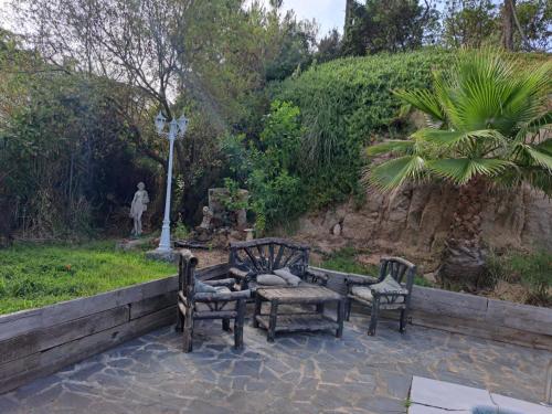 a patio with two chairs and a bench and a cross at Villa LLoret Blau in Lloret de Mar
