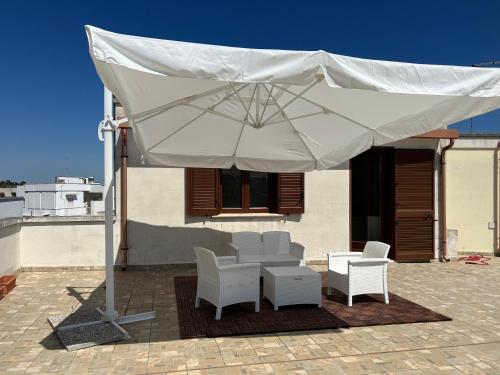 un ombrellone bianco su un patio con sedie e tavolo di FH HOLIDAYS SALENTO a Sternatia