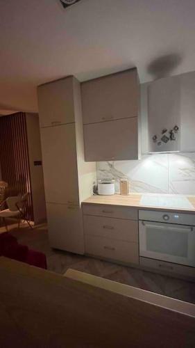Una cocina con gabinetes blancos y encimera. en Apartament Centrum Ligota, en Katowice