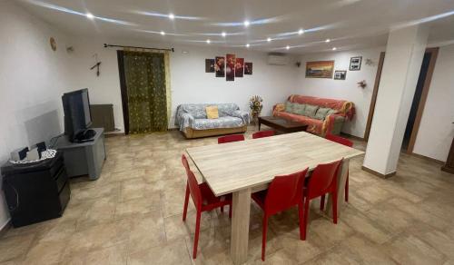 uma sala de estar com uma mesa de madeira e cadeiras vermelhas em Casa vacanze vicino Otranto em Giurdignano