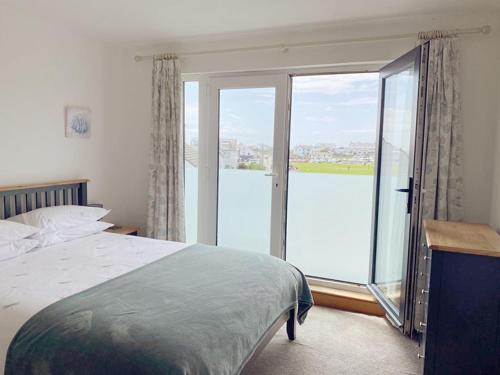 a bedroom with a bed and a large glass window at 1 Y Bae - Top Floor Apartment in Trearddur