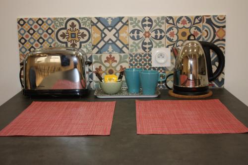 einen Tisch mit zwei Matten, einem Toaster und Tassen in der Unterkunft Appartement Cœur de Ville - Saint Germain en Laye in Saint-Germain-en-Laye