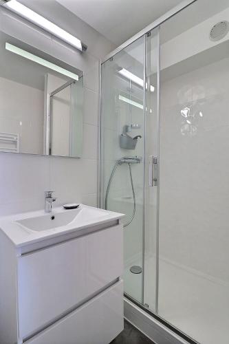 une salle de bain blanche avec un lavabo et une douche dans l'établissement Cosy Deauville Studio, à Deauville